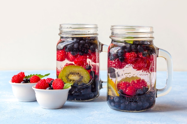 Bebida fresca fresca de desintoxicação com framboesas, mirtilos e kiwi em caneca de vidro. limonada em um copo com uma hortelã. o conceito de nutrição adequada e alimentação saudável. dieta fitness