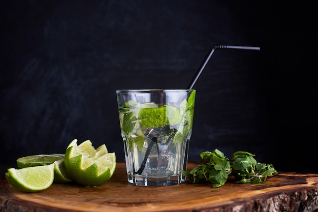 Bebida fresca con limón, menta y hielo en la mesa de madera oscura