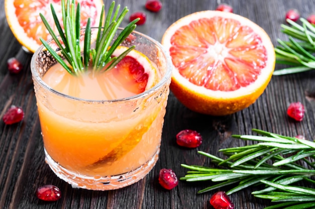 Bebida fresca del verano con la naranja y el romero de sangre en un vidrio en fondo de madera oscuro.