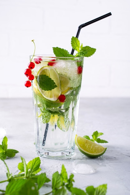 Foto bebida fria de verão, sangria, limonada ou mojito com limão fresco de groselha, folhas de hortelã limão com ingredientes.
