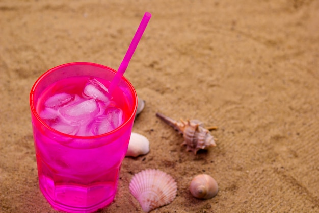 Bebida fría con hielo en una playa de arena