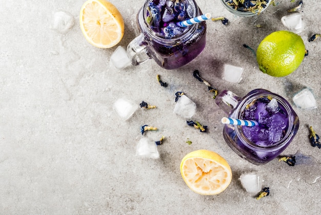 Bebida fría de verano saludable, té de flor de guisante de mariposa azul y violeta orgánico helado con limas y limones