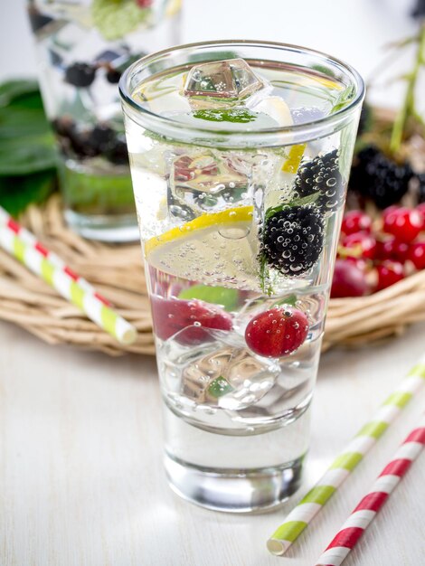 Foto bebida gaseosa detox con limón y frutos rojos frescos