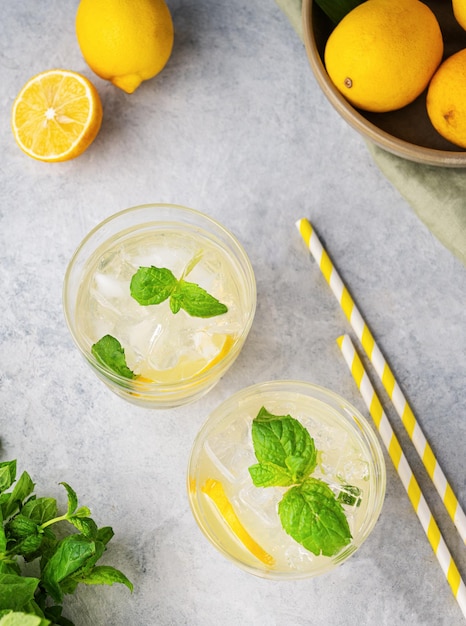 Bebida gaseosa de limonada con limones frescos Cócteles refrescantes con menta de limón y hielo en vaso sobre fondo texturizado Concepto de bebidas frías de verano Vista superior