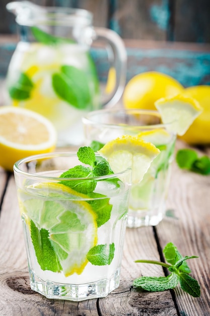 Bebida gelada de verão com limão e hortelã na mesa rústica de madeira