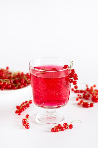 Bebida de grosella roja en vaso Bebida de verano Sabrosa bebida de verano Fondo blanco Desintoxicación Agua infundida Vertical