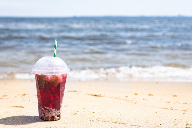 Bebida de hielo refresco de limonada roja en la playa jugo fresco de cereza o fresa orilla del mar ola de surf de verano