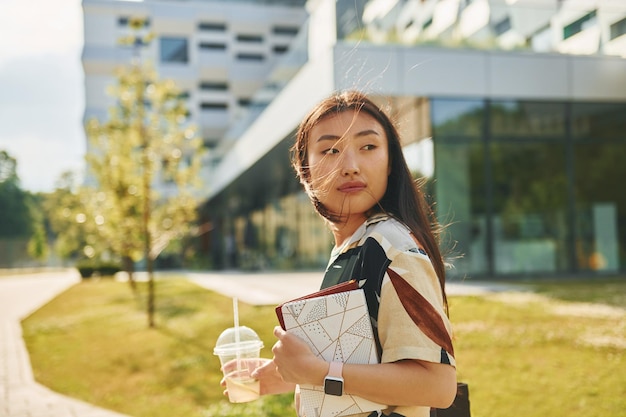 Con bebida Joven asiática está al aire libre durante el día