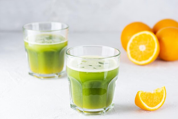 Bebida de jugo de naranja y matcha en vasos sobre una mesa de luz.