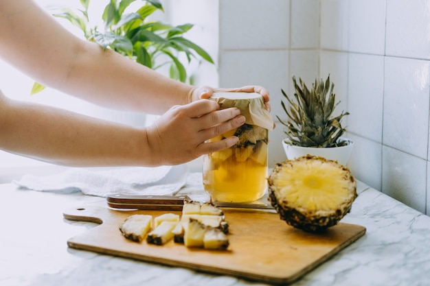 Bebida de kombucha de piña fermentada tepache. Proceso de cocción de la bebida de piña de superalimento probiótico casero. Beba tarro y piña en rodajas en la cocina de casa.