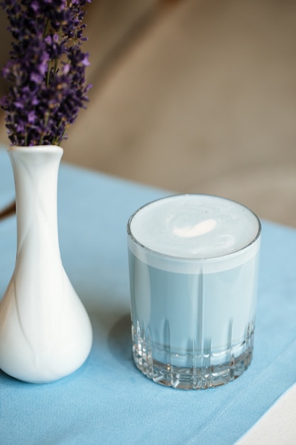 Bebida con leche azul lavanda en un vaso sobre la mesa con flores