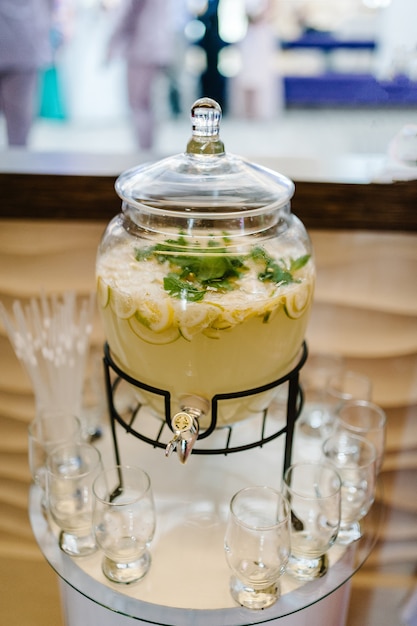 Bebida de limonada de agua con gas con hielo, limón y hojas de menta en jarra sobre fondo de mesa rústica. Tarro de vasos de casera.