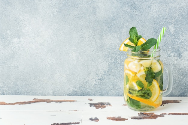 Bebida de la limonada del agua de soda, del limón y de las hojas de menta en tarro en fondo ligero.