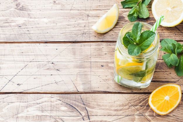 Bebida de la limonada del agua de soda, del limón y de las hojas de menta en tarro en fondo de madera. Copia espacio