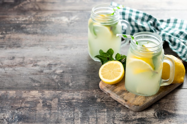 Bebida de limonada en un frasco de vidrio e ingredientes en una mesa de madera