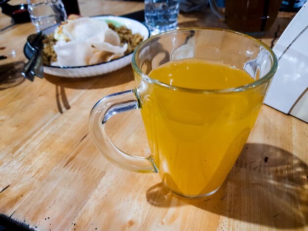 Foto bebida de naranja exprimida en un vaso sobre la mesa