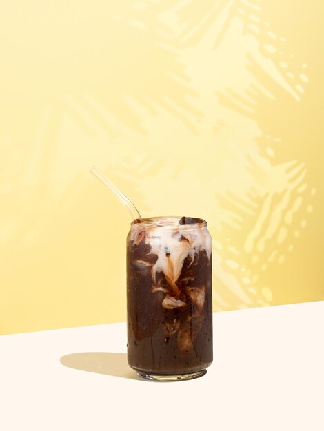 Bebida natural de cacau frio com leite não lácteo em um fundo de projeção diagonal isométrica amarela Copo de cacau em forma de lata com canudo de vidro Conceito de bebidas sustentáveis de verão