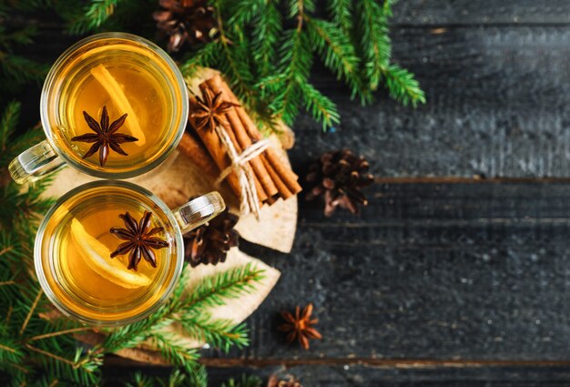 Bebida de Navidad grog con limón, canela, vino en mesa de madera con ramas de abeto y espacio de copia