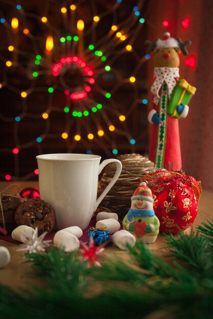 Bebida navideña con galleta casera de chocolate decorada con luces brillantes y juguetes