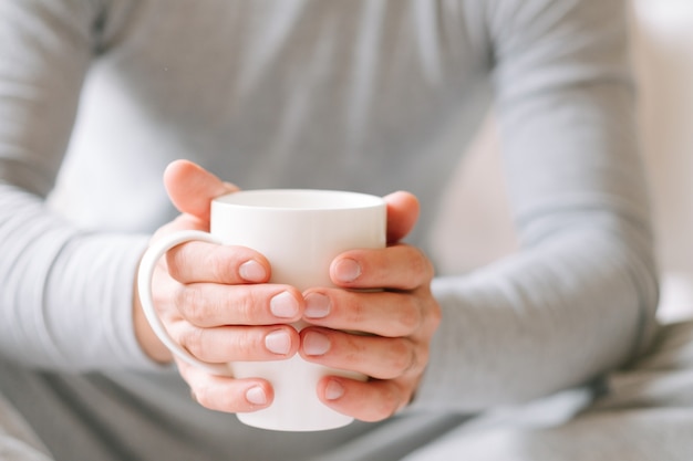 Bebida para acordar. homem sentado e segurando uma xícara branca de chá quente da manhã.
