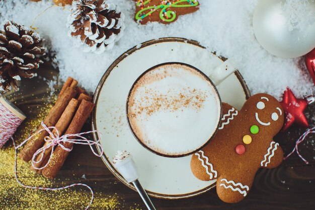 Bebida quente de chocolate ou cacau com biscoito de canela e gengibre em fundo de mesa de madeira vintage de neve