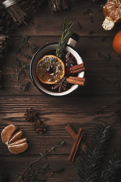 Foto bebida quente de natal com vinho quente na mesa de madeira com canela, cravo, especiarias.