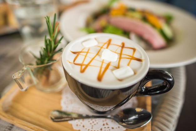 bebida quente e espuma de leite no copo com calda de caramelo e marshmallow no topo