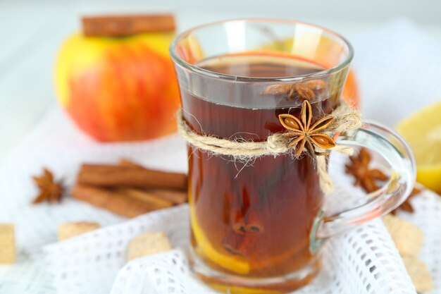 Bebida quente em copo de vidro com frutas e especiarias, em fundo de madeira