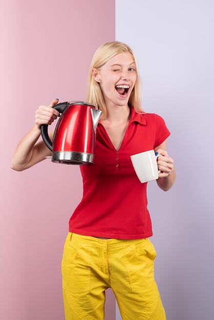 Bebida quente feliz sorrindo atraente jovem dona de casa derramando e fazendo chá usando eletricidade