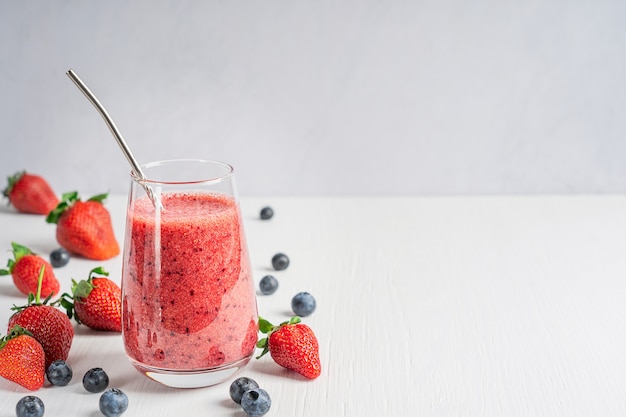 Bebida refrescante batida hecha de puré de fresas jugosas dulces maduras y arándanos en vidrio