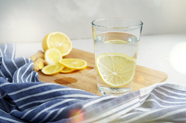 Bebida refrescante com limão. água morna com uma fatia de limão ao lado de um guardanapo azul