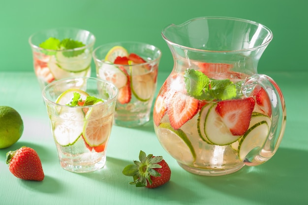 Bebida refrescante de verão com limão pepino morango na jarra e copos