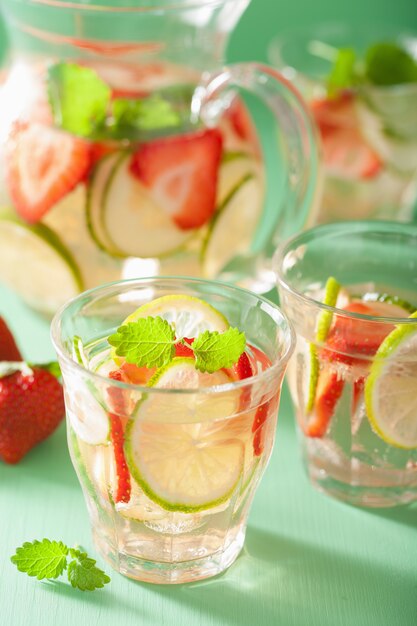 Bebida refrescante de verão com limão pepino morango na jarra e copos