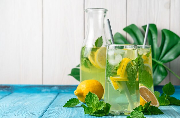 Bebida refrescante e saudável de verão, sobre um fundo claro com espaço para copiar. Limão com gelo, hortelã e rodelas de limão.