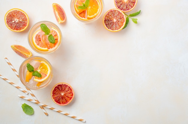 Bebida refrescante fría con rodajas de naranja sanguina en un vaso sobre un hormigón blanco Vista superior, plano, copia espacio.