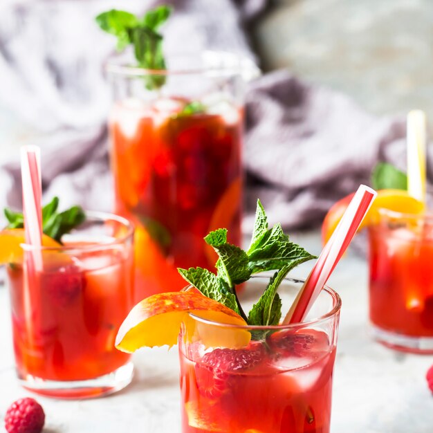 Bebida refrescante ligera de verano con frutas y bayas - sangría. En vasos sobre una mesa gris.