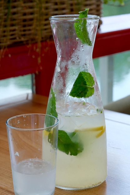 Bebida refrescante limonada con hojas de menta y hielo en una mesa de café en un día soleado de verano