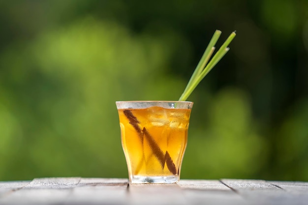 Bebida refrescante saludable de canela y tallos de limoncillo en una mesa de madera en un jardín tropical