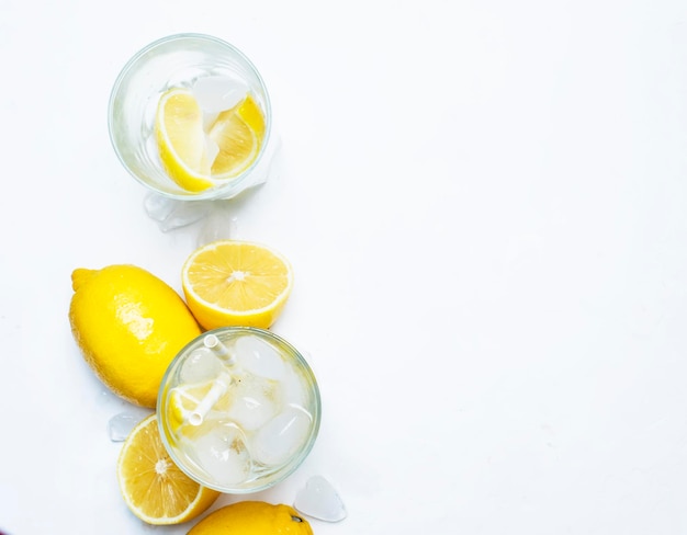 Bebida refrescante de verano agua fría con hielo y limón vista superior de fondo blanco