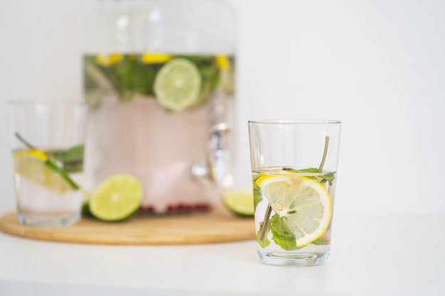 Bebida refrescante de verano con bayas y limonada cítrica en una botella de vidrio reutilizable y vasos homemad ...