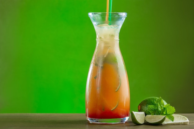 Bebida refrescante de verano con lima naranja y hielo en un decantador