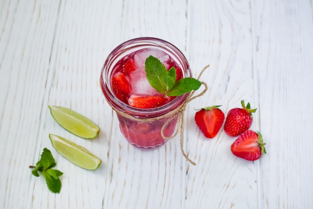 Bebida roja de verano con fresas, hielo y menta con limón