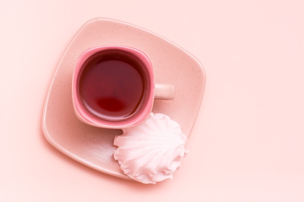 Bebida rosa en una taza de café y malvaviscos en un platillo.