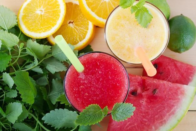 Bebida saludable batidos rojos y amarillos con jugosas rodajas de sandía y naranjas