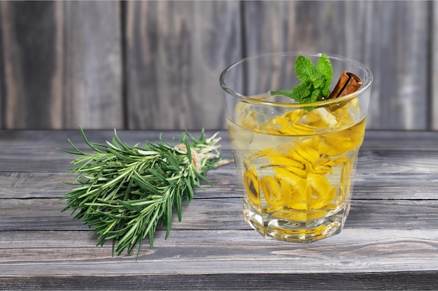 Bebida saludable con limón y canela con hierba de romero en fondo de mesa de madera