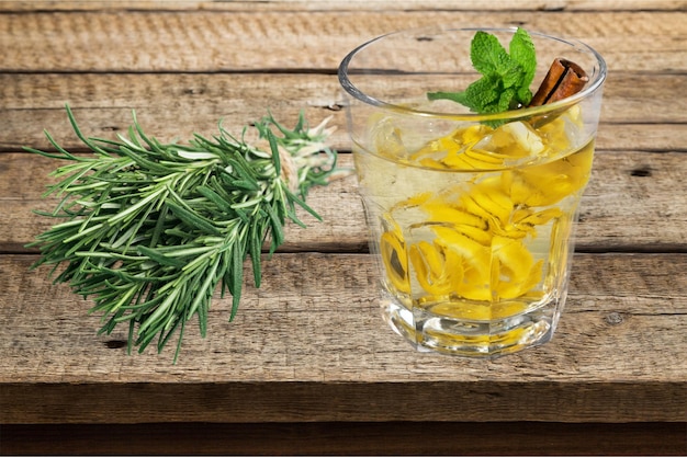 Bebida saludable con palitos de limón y canela, hierba de romero sobre fondo de mesa de madera