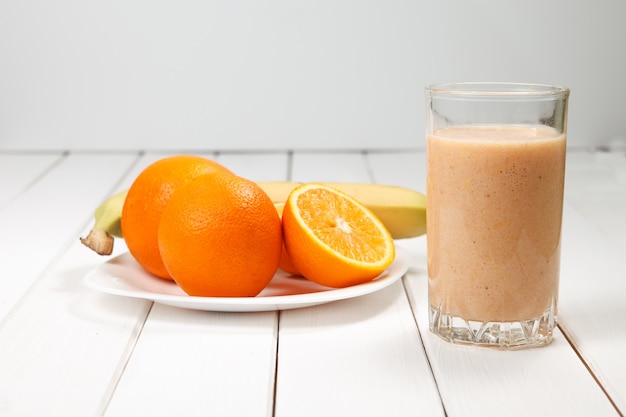 Bebida saudável laranja e banana batidos na mesa de madeira