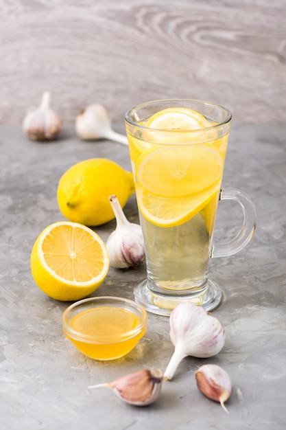 Bebida terapéutica de limón, miel y ajo en un vaso sobre la mesa.