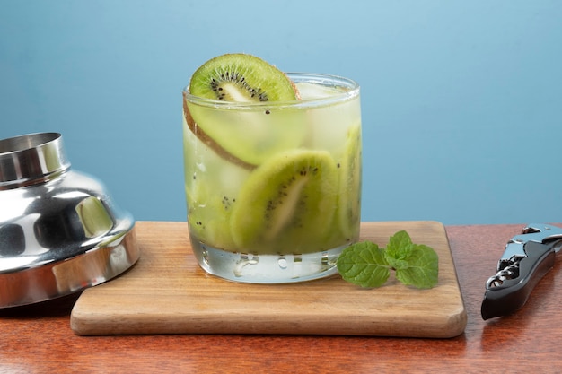 Bebida típica brasileña Caipirinha con kiwi en la mesa de corte de madera