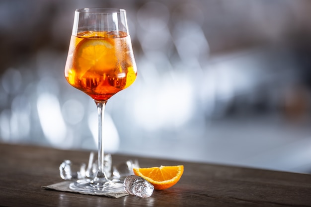 Bebida típica de verano aperol spritz servido en copa de vino con aperol, prosecco, refresco y una rodaja de naranja.